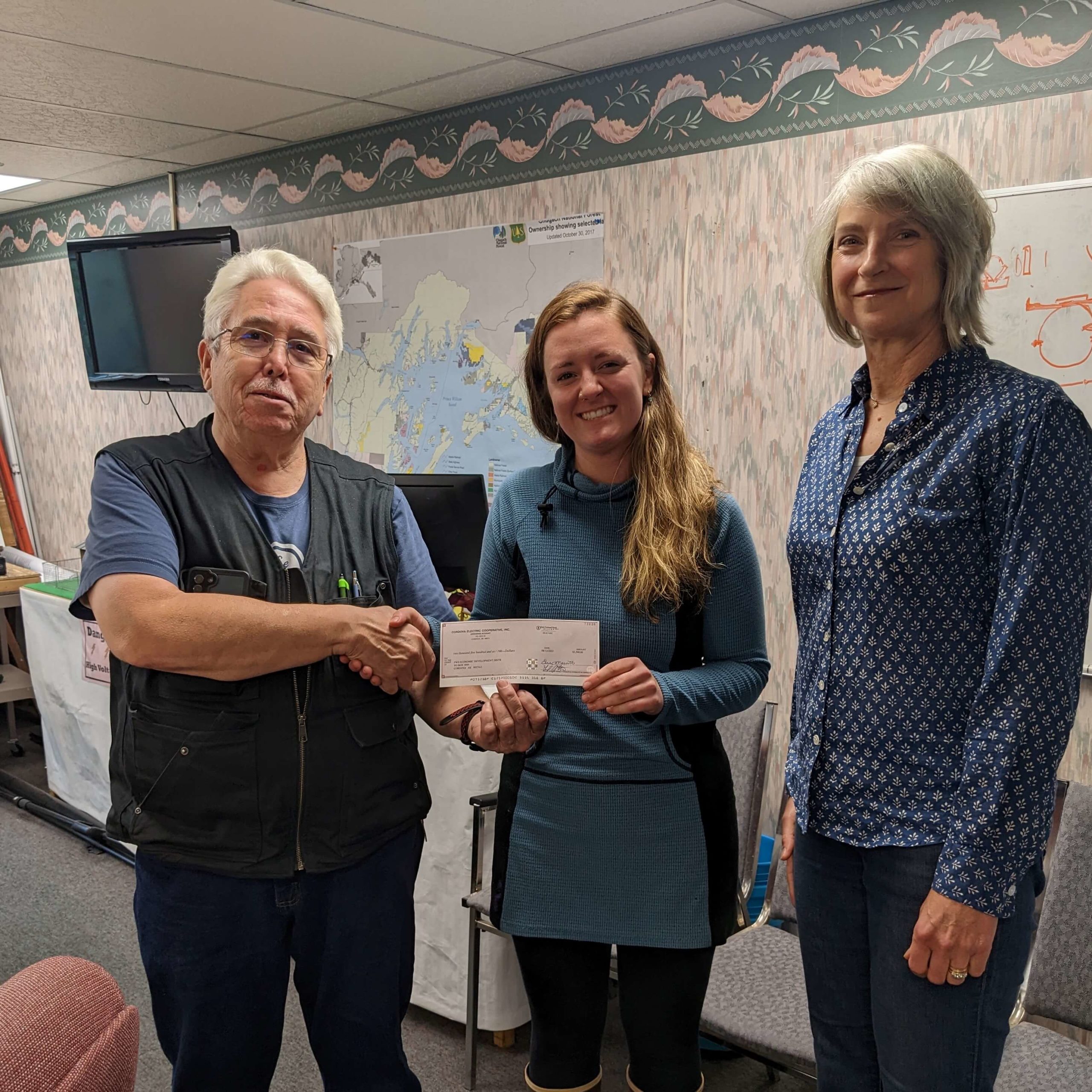 Joe Cook presents check to Gabrielle Brown and Kristin Carpenter for Alaska Adventure Learning